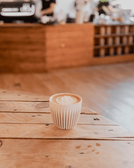 a flat white coffee with latte art on a wooden table in a coffee shop