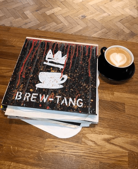 a barista coffee on a table next to a book with 'brew tang' written on it