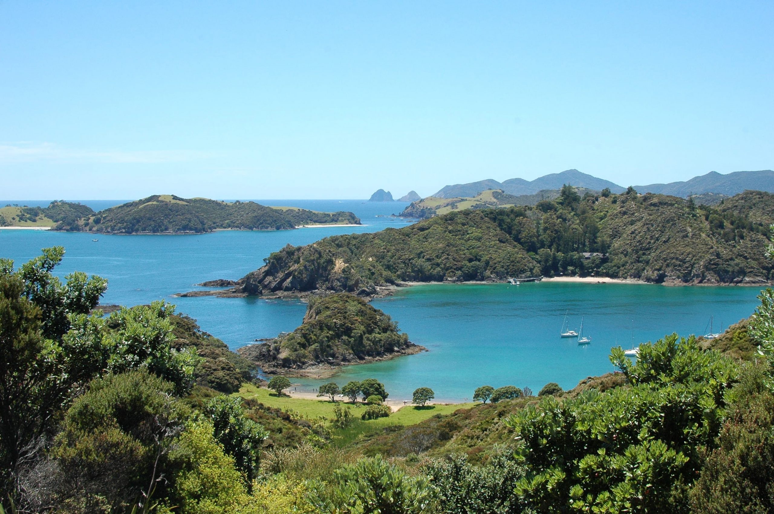 A viewpoint overlooking small tree-covered islands and blue ocean dotted with small sailing boats.