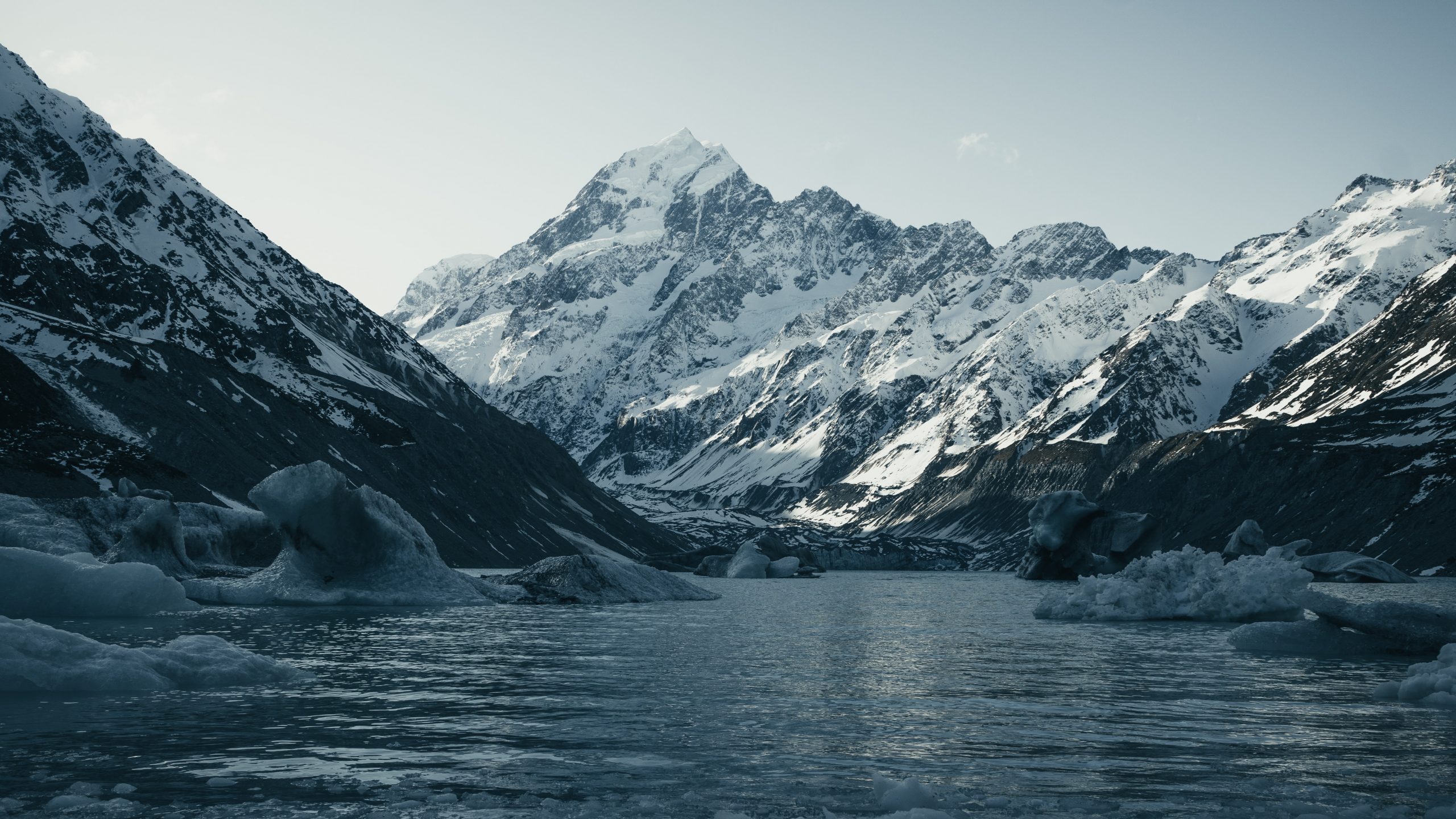 A glacial lake with ice floating in it flanked by a 3000 metre snow-capped mountain.
