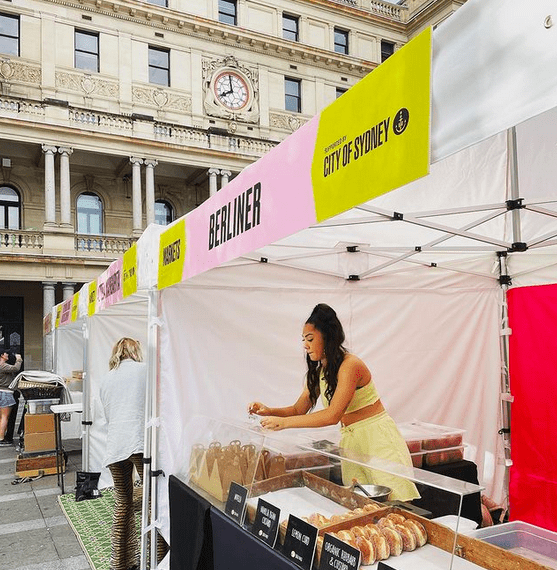 A woman packing donuts at a donut stall in a city.
