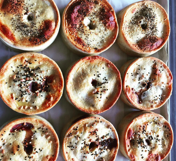 An overhead shot of baked pies with poppy seeds on the top and filling seeping out of the hole.