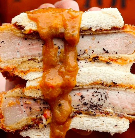 A double pork katsu sandwich with katsu sauce dripping down the middle.